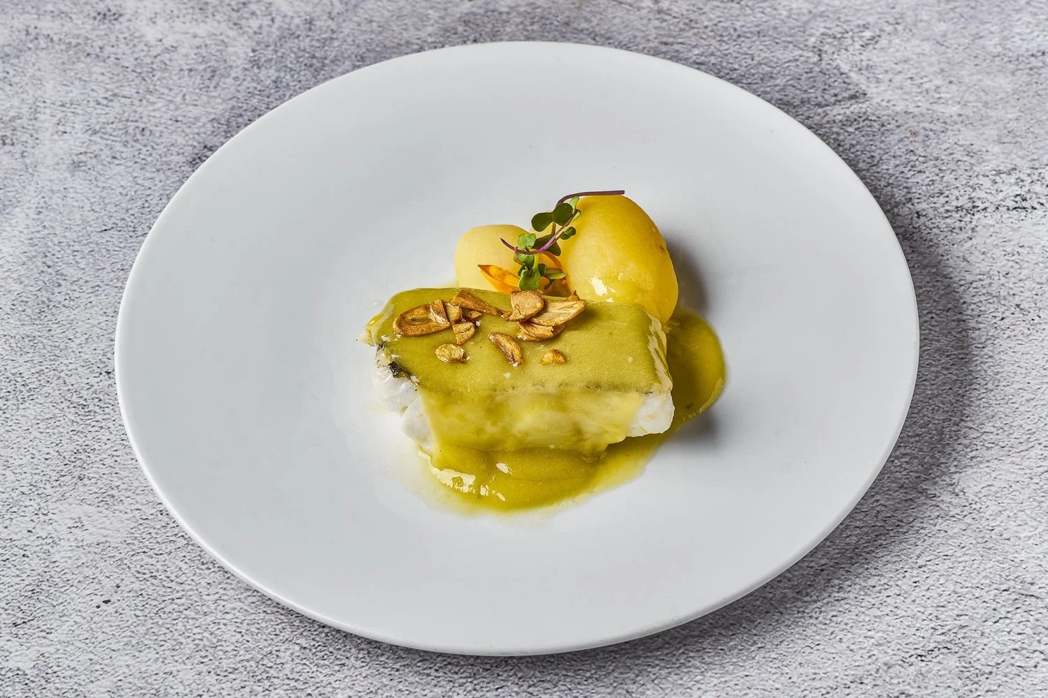 Bacalao con salsa verde en plato blanco