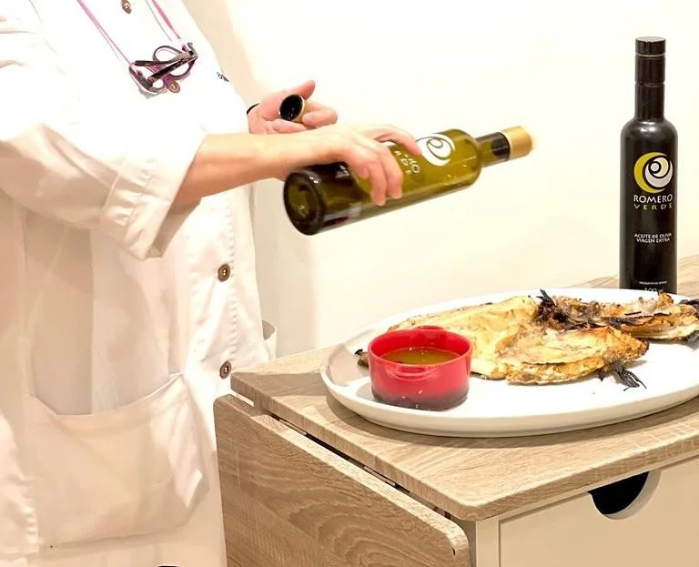 Cocinera de Ogrelo aliñando un plato con aceite de oliva