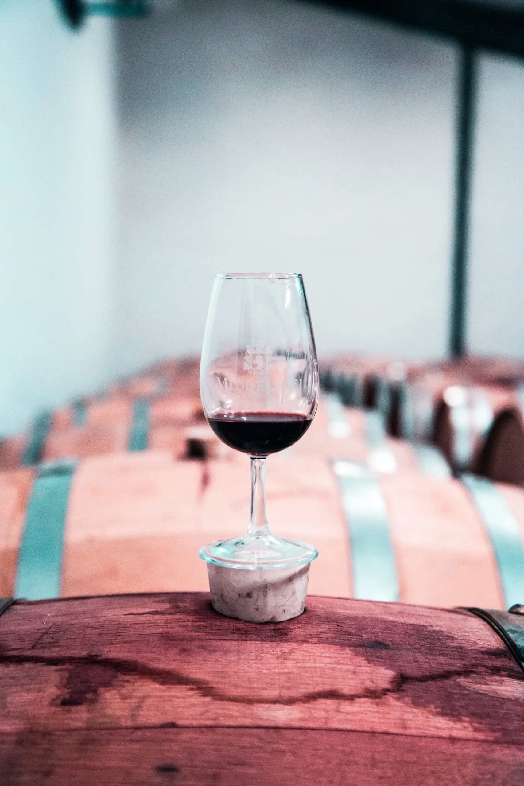 Copa de vino tinto sobre una barrica