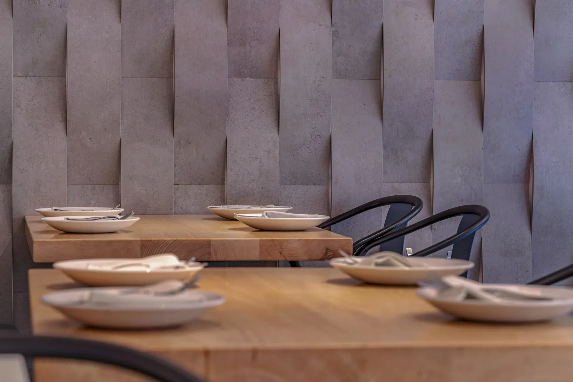 Wooden tables set with tableware in front of a gray stone wall