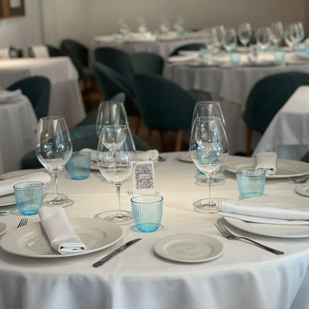 Mesas redondas con copas y vasos azules en el comedor