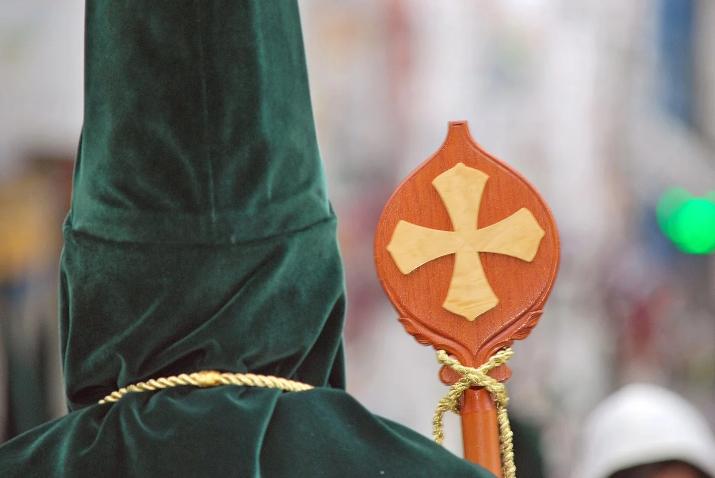Nazareno con capirote verde y cruz en una procesión