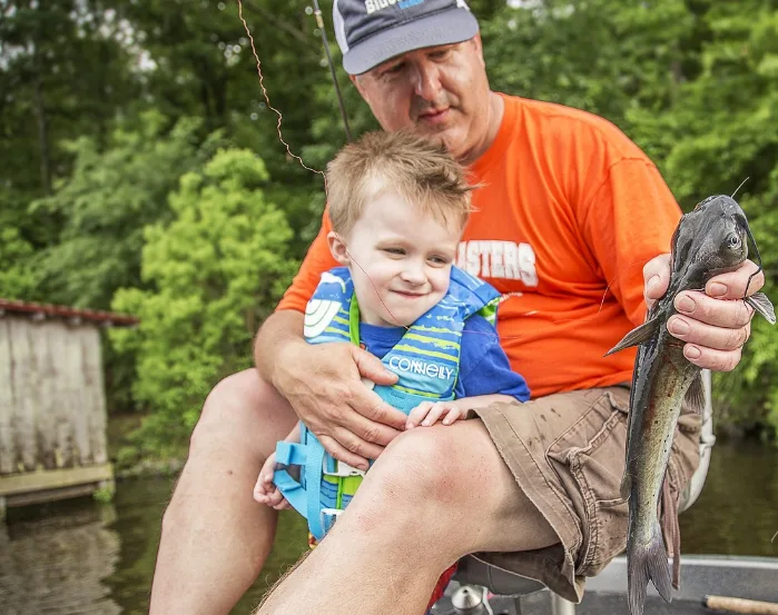 Padre con su hijo sosteniendo un pez en un río